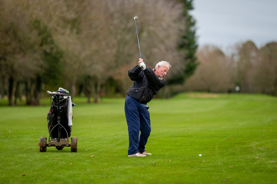 a man swings at a golf ball in the fairway
